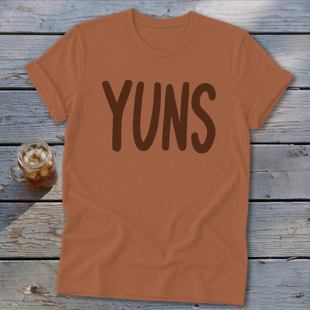 Brown text "YUNS" on a rust-colored t-shirt with a drink.