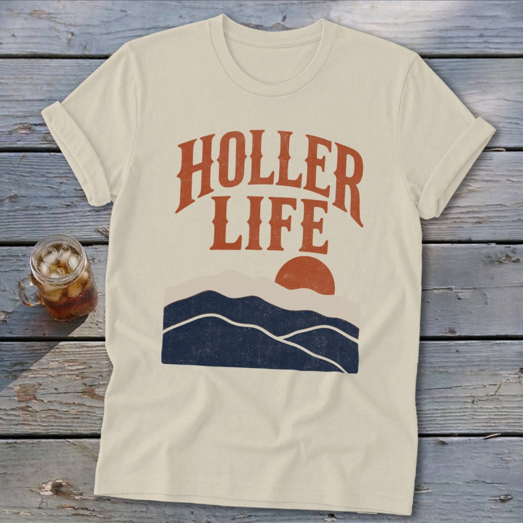 A beige t-shirt with the text HOLLER LIFE above a graphic of mountains and a sun.
