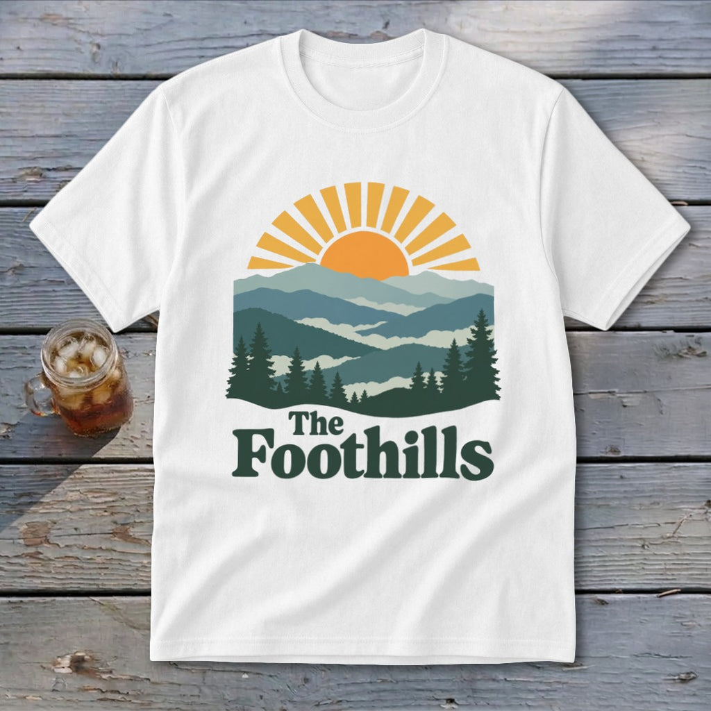 White t-shirt with a stylized mountain landscape and "The Foothills" text.