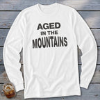 White long-sleeve shirt with black text reading "AGED IN THE MOUNTAINS".