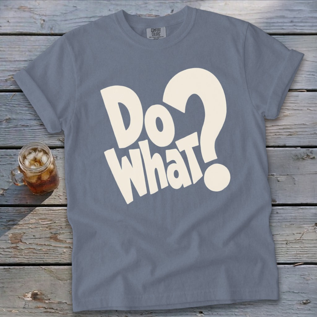 A blue t-shirt featuring the white text "Do what?" on a wooden background with a glass drink.