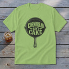 Light green t-shirt with cast iron skillet graphic saying "Cornbread Ain't Cake".