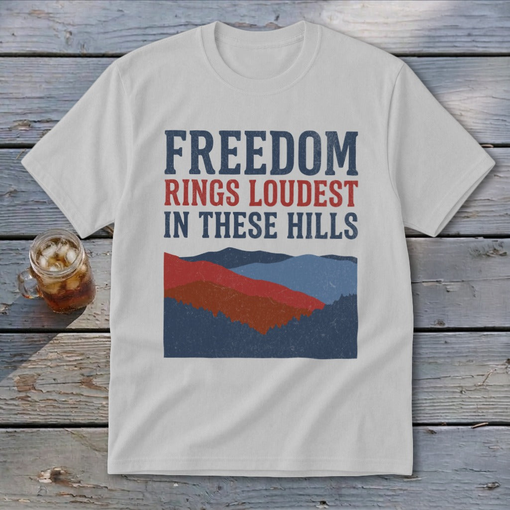 Light gray t-shirt with the red and blue text Freedom Rings Loudest in These Hills above layered mountain graphics.
