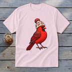 A light pink t-shirt displays an illustration of a bright red cardinal wearing a winter beanie.