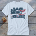 White t-shirt with distressed American flag graphic and text: "Alabama Raised American Made".