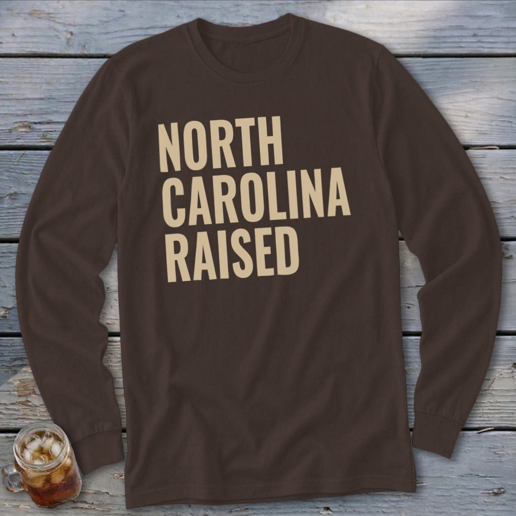 Brown long-sleeve shirt with "NORTH CAROLINA RAISED" in beige text.