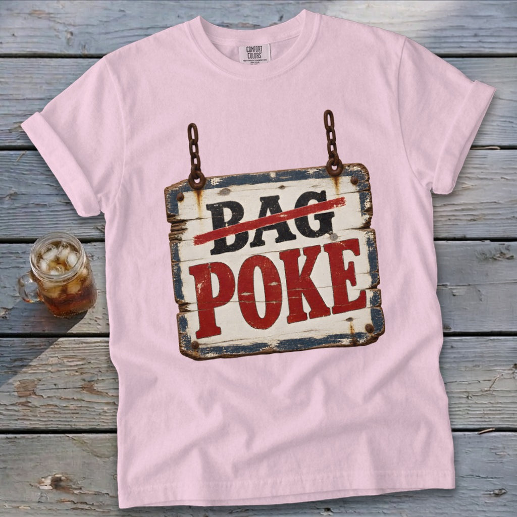 A light pink t-shirt featuring a rustic wooden sign graphic that reads BAG POKE on a wooden background.