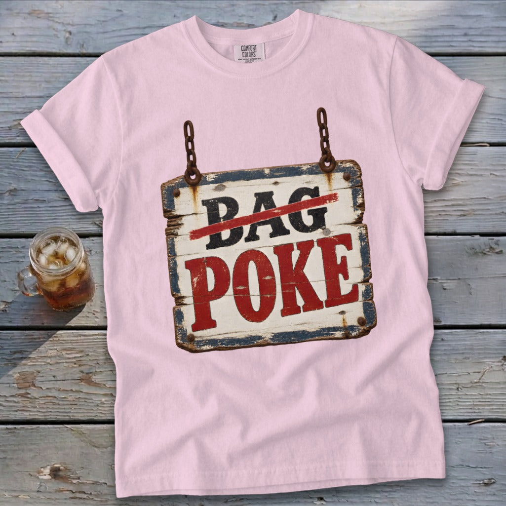 A light pink t-shirt featuring a rustic wooden sign graphic that reads BAG POKE on a wooden background.