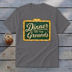 Dark gray t-shirt featuring a green sign graphic with lit bulbs and Dinner on the Grounds text.