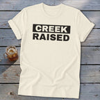 Cream t-shirt with "CREEK RAISED" in black text.