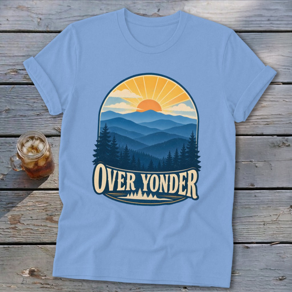 Light blue t-shirt featuring a mountain sunset graphic and the text OVER YONDER, displayed on a wooden surface.