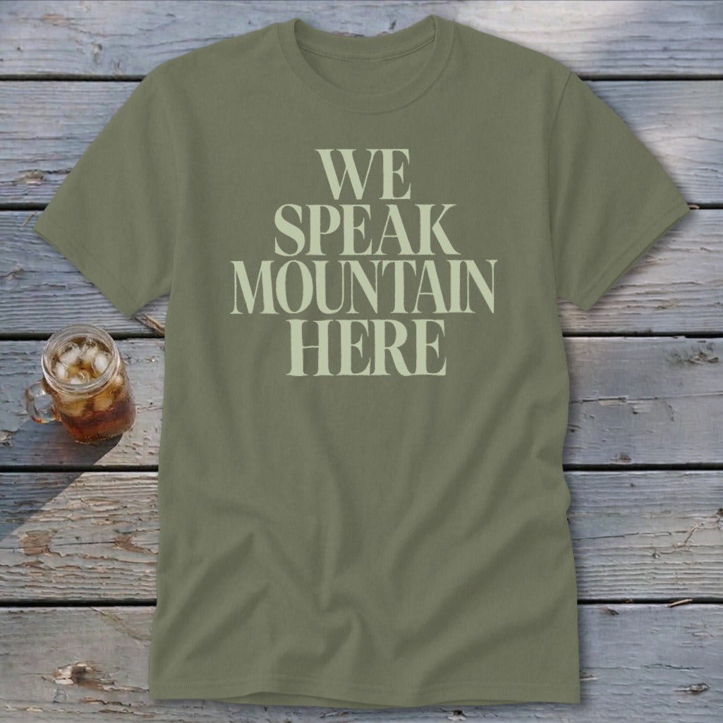 Olive green t-shirt with text "WE SPEAK MOUNTAIN HERE" in cream font.