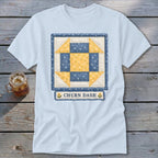 Light blue t-shirt with a blue and yellow "Churn Dash" quilt block design.