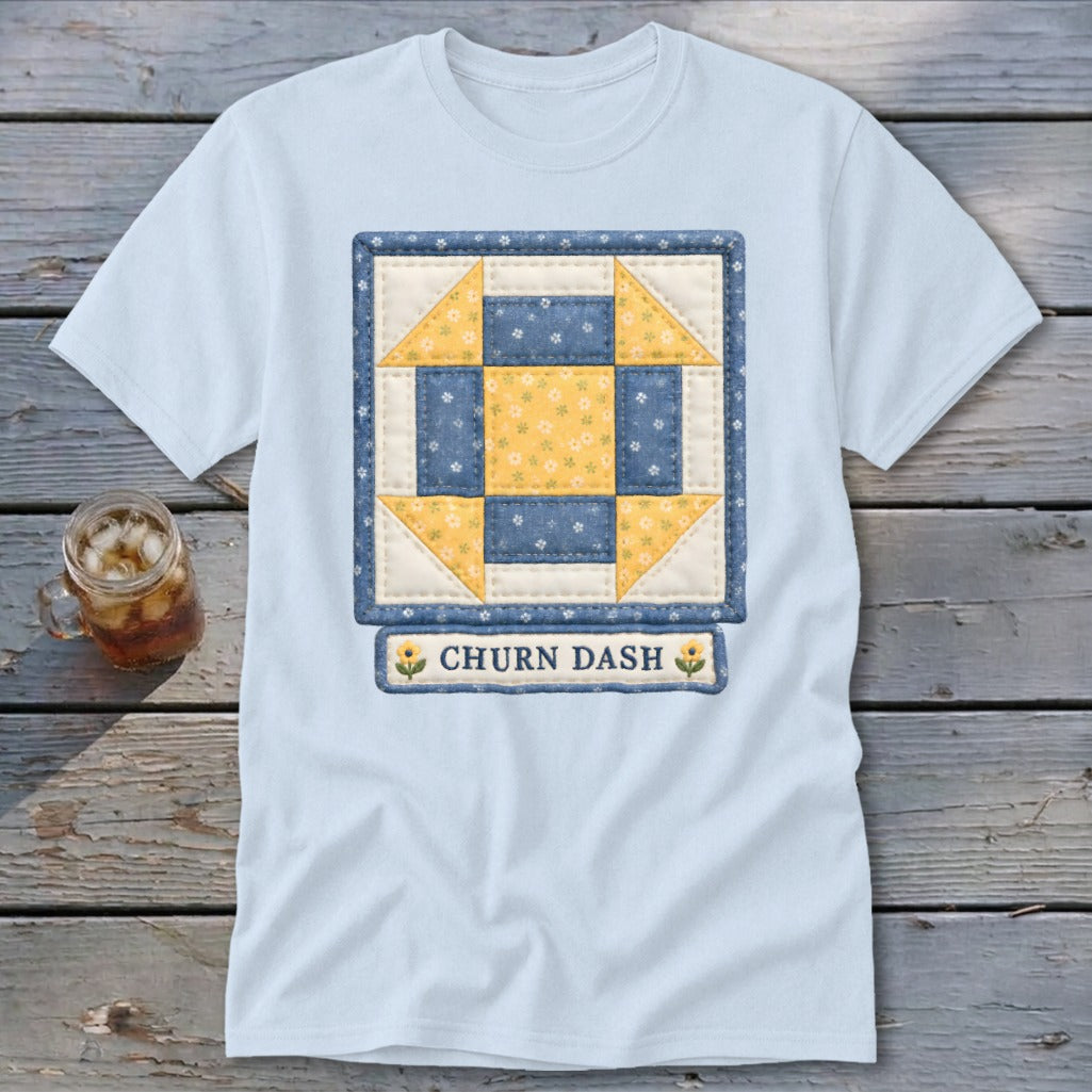 Light blue t-shirt with a blue and yellow "Churn Dash" quilt block design.
