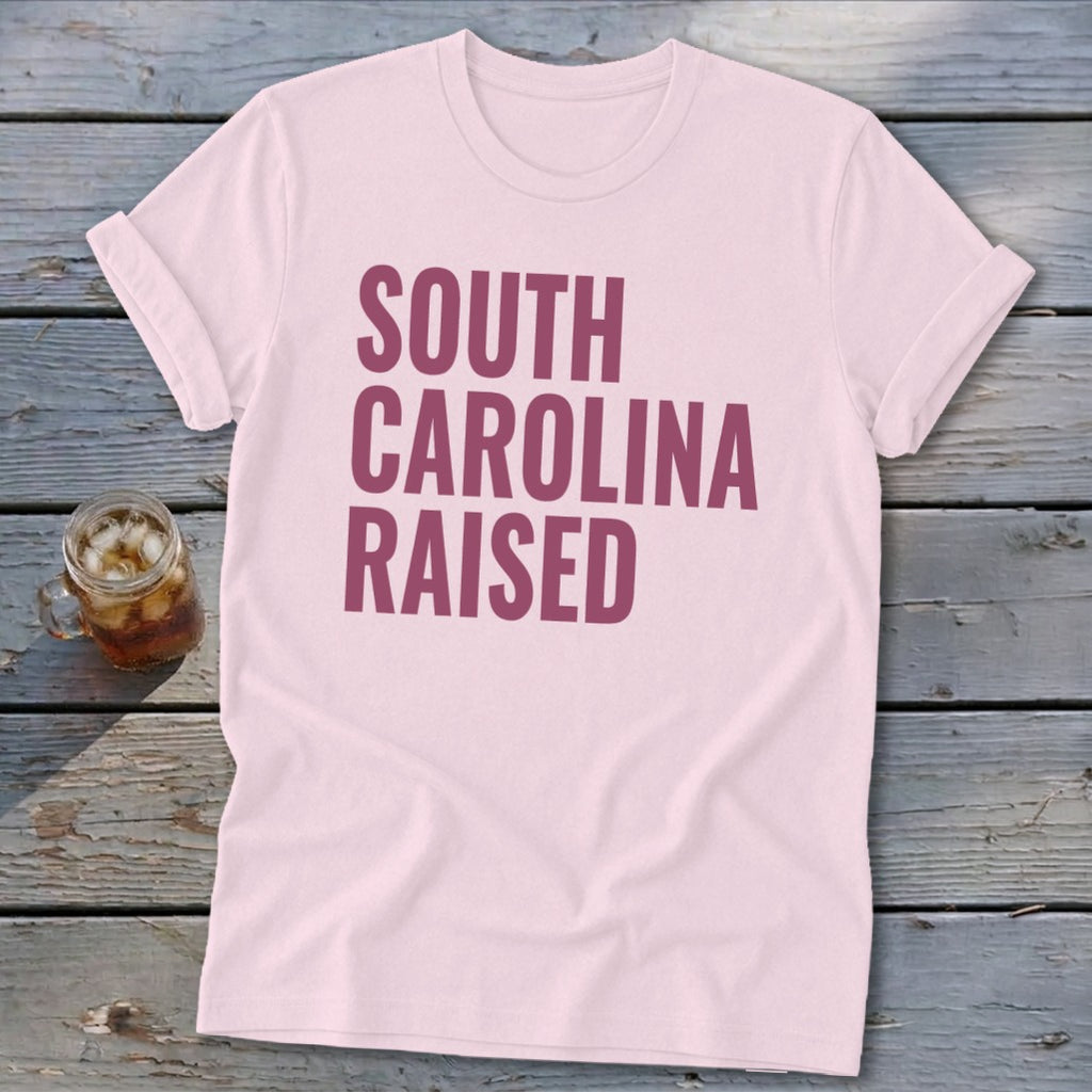 Pink t-shirt with "South Carolina Raised" text in maroon.