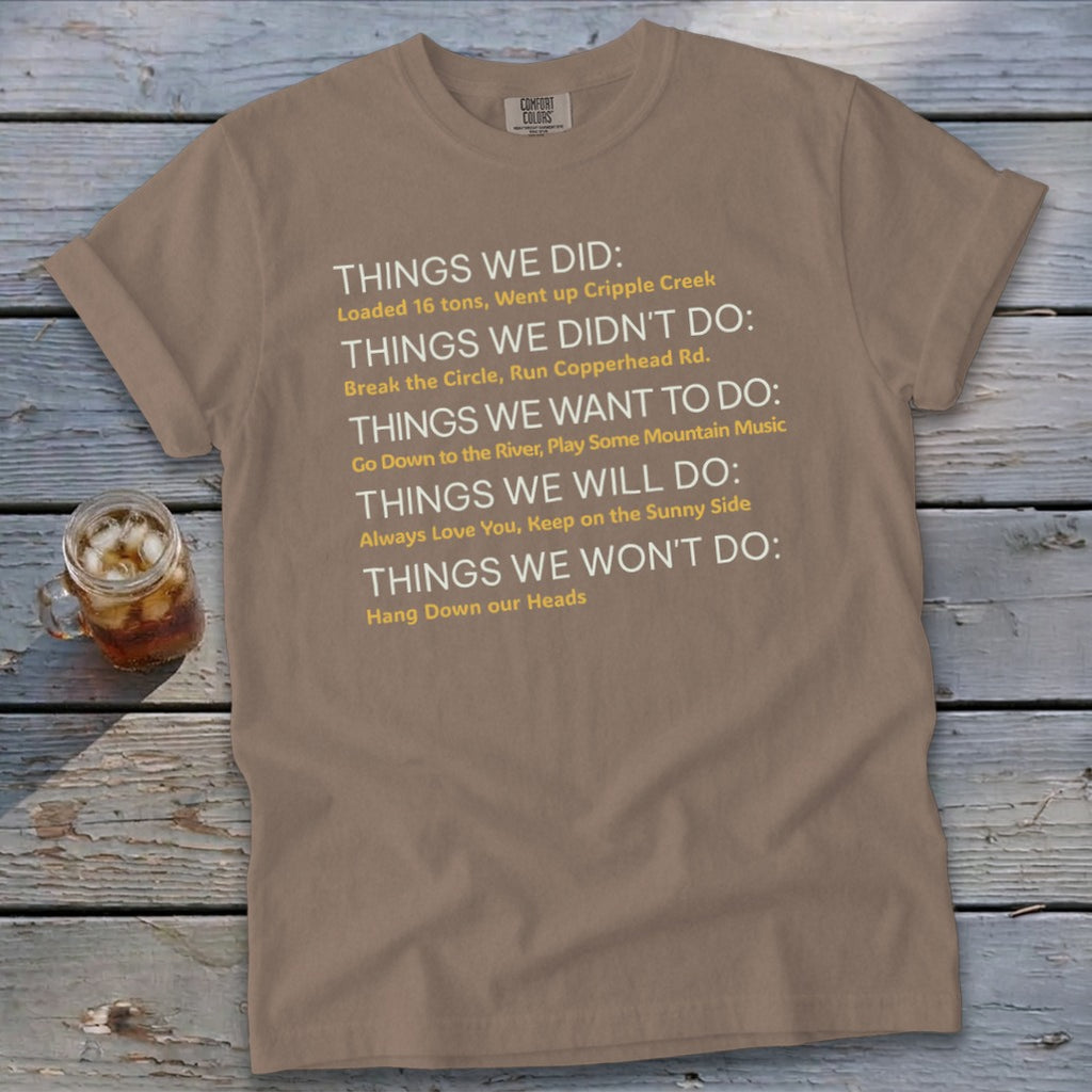 Brown t-shirt with white and yellow text listing "Things we did" and other phrases.