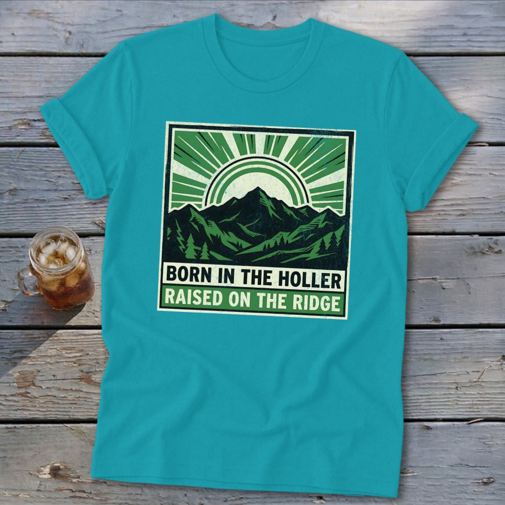 A bright teal t-shirt featuring a green graphic of mountains, trees, and the text Born in the Holler Raised on the Ridge.
