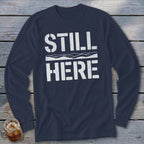 Navy long-sleeve shirt with white text "STILL HERE" and wave graphic.