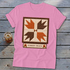 Pink t-shirt with a "Turkey Track" quilt block design and floral accents.