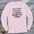 Pink long sleeve shirt with black text that reads "I don't count Birthdays I COUNT YEARS OF CORN".