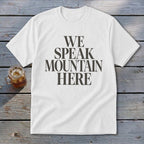 White t-shirt with "WE SPEAK MOUNTAIN HERE" text and a glass of iced tea.