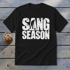 A black t-shirt with distressed white text reading SANG SEASON, featuring a person digging with a shovel.