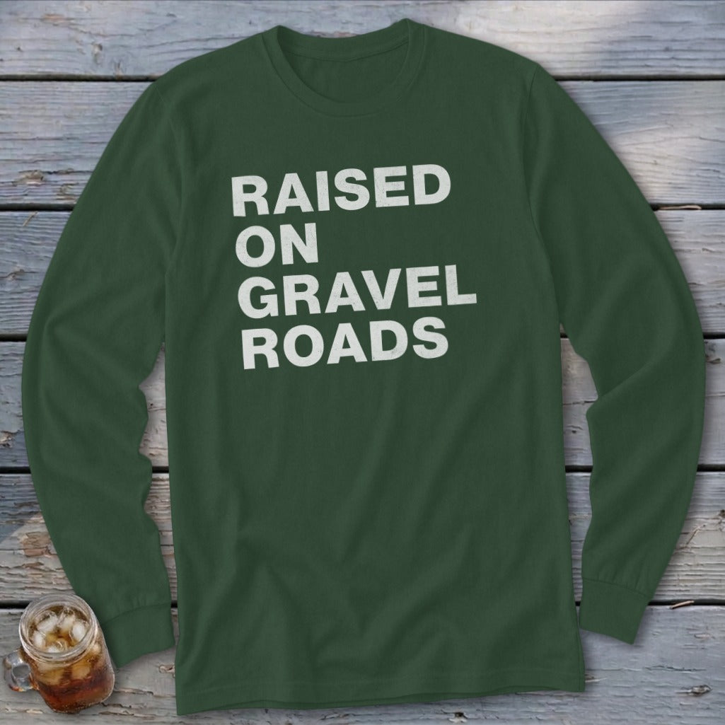 Dark green long-sleeve shirt with white text reading "RAISED ON GRAVEL ROADS".