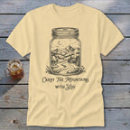 Pale yellow t-shirt featuring a mason jar graphic containing a mountain landscape and text Carry The Mountains With You.