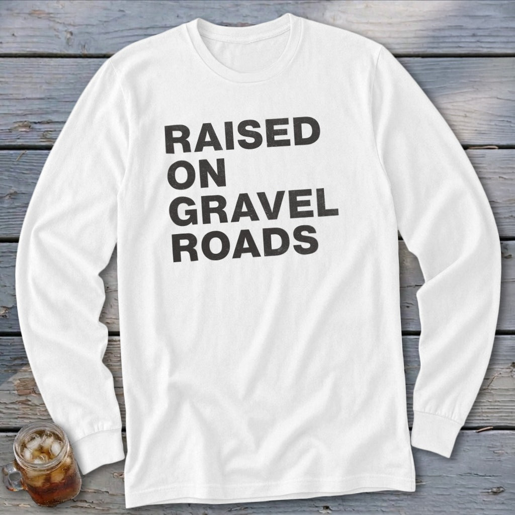 White long sleeve shirt with black text reading "RAISED ON GRAVEL ROADS".