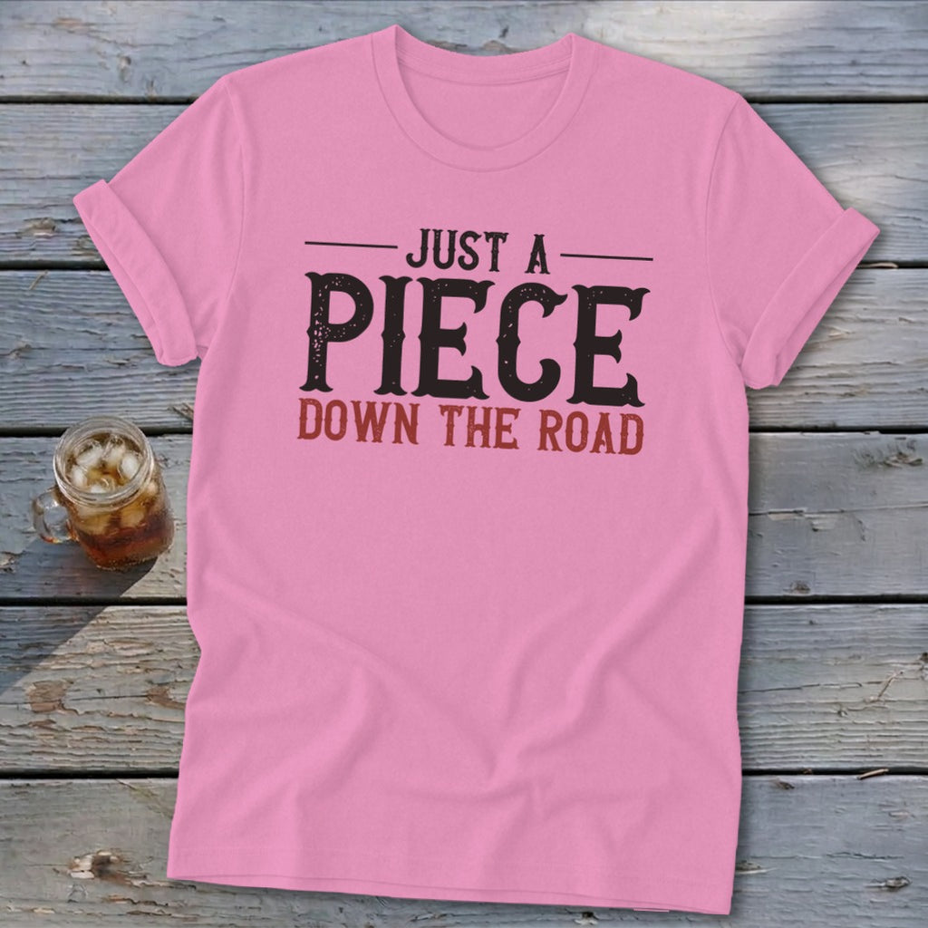 Pink t-shirt with text "JUST A PIECE DOWN THE ROAD"