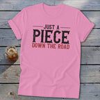 Pink t-shirt with text "JUST A PIECE DOWN THE ROAD"