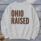 White crewneck sweatshirt with brown text "OHIO RAISED"