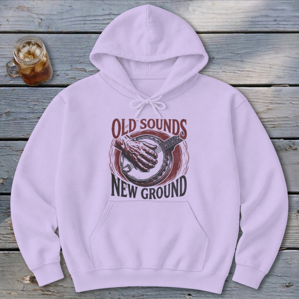 A light purple hooded sweatshirt features a vintage graphic with the text Old Sounds New Ground and a banjo on a wooden surface.