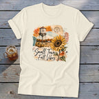 Cream t-shirt with "Small Town Fall Vibes" graphic featuring a sunflower and water tower.