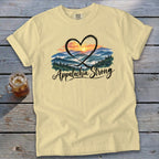 Light yellow t-shirt with "Appalachia Strong" and mountain sunset graphic inside a heart.