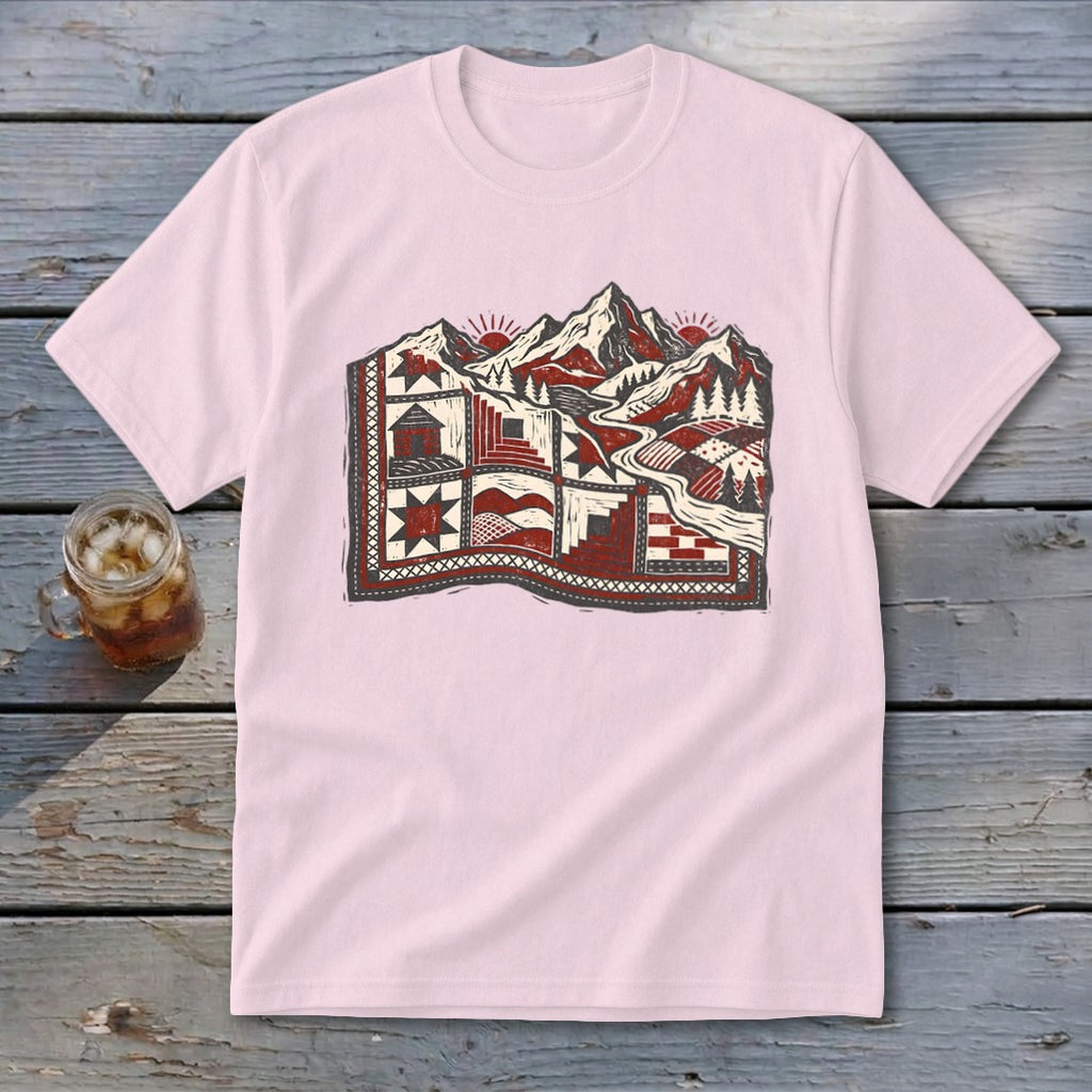 Light pink short-sleeved t-shirt featuring a red and grey graphic of a mountainous landscape with quilts.