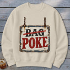 A beige crewneck sweatshirt features a graphic of a rustic wooden sign hanging by chains with text reading "BAG POKE".