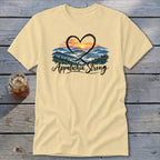 Light yellow t-shirt with a heart encompassing a mountain sunset and "Appalachia Strong" text.