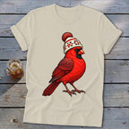Beige t-shirt featuring an illustration of a red cardinal wearing a winter knit hat.