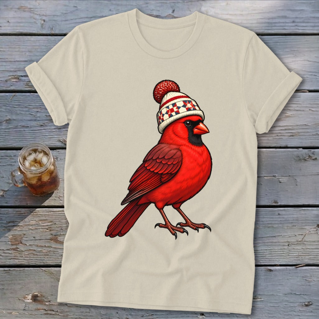 Beige t-shirt featuring an illustration of a red cardinal wearing a winter knit hat.