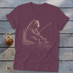 Brown bear fishing by the water on a maroon t-shirt.