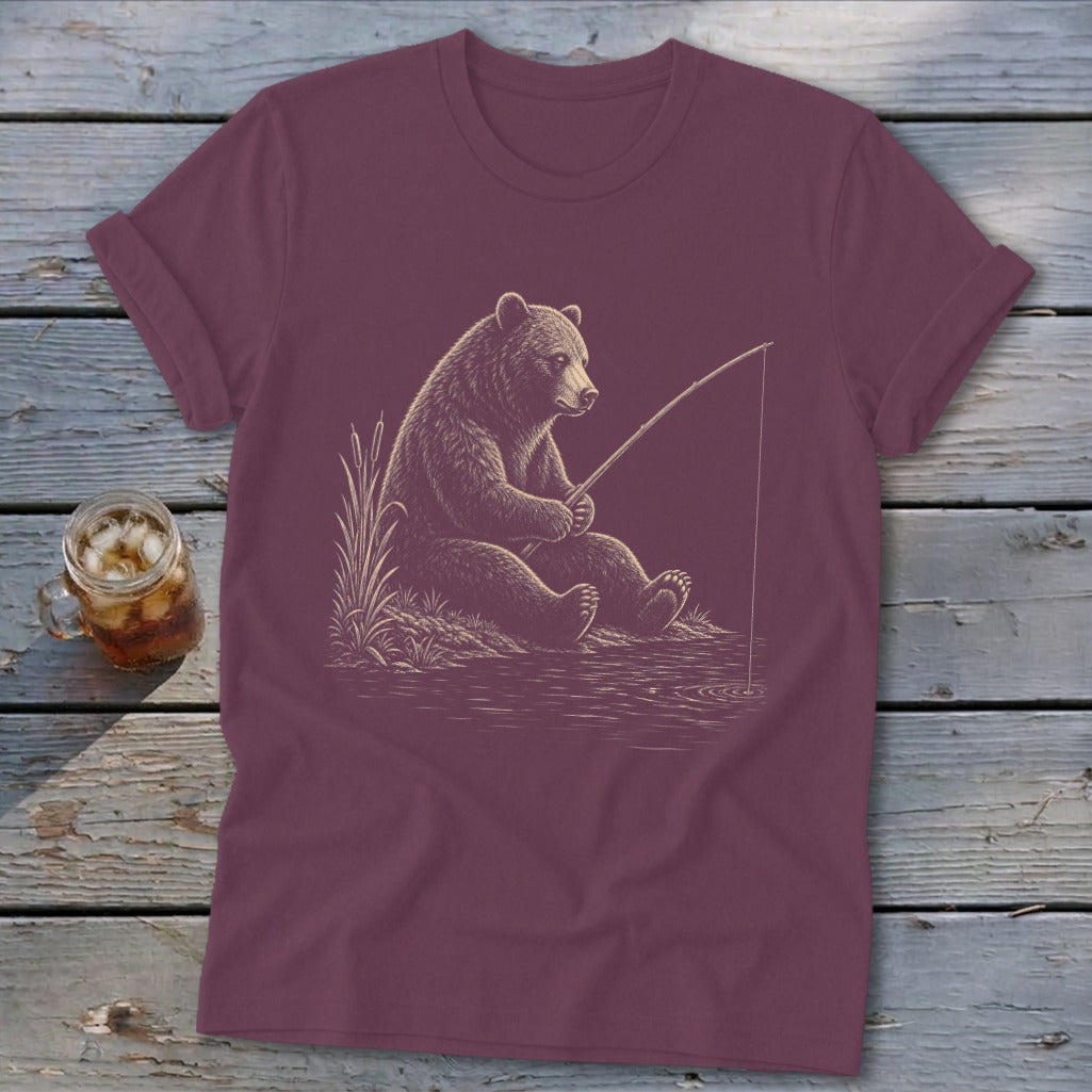 Brown bear fishing by the water on a maroon t-shirt.