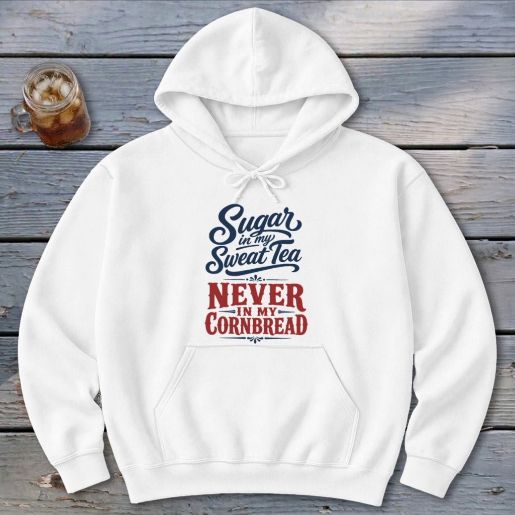 A white hooded sweatshirt featuring blue and red text reading Sugar in my Sweet Tea Never in my Cornbread on a wooden background.