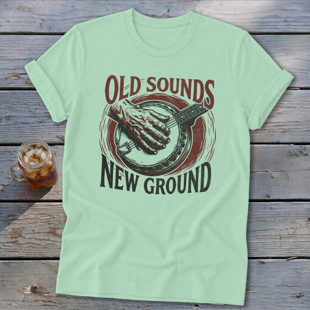 Light green t-shirt featuring a banjo graphic and text that reads Old Sounds New Ground.