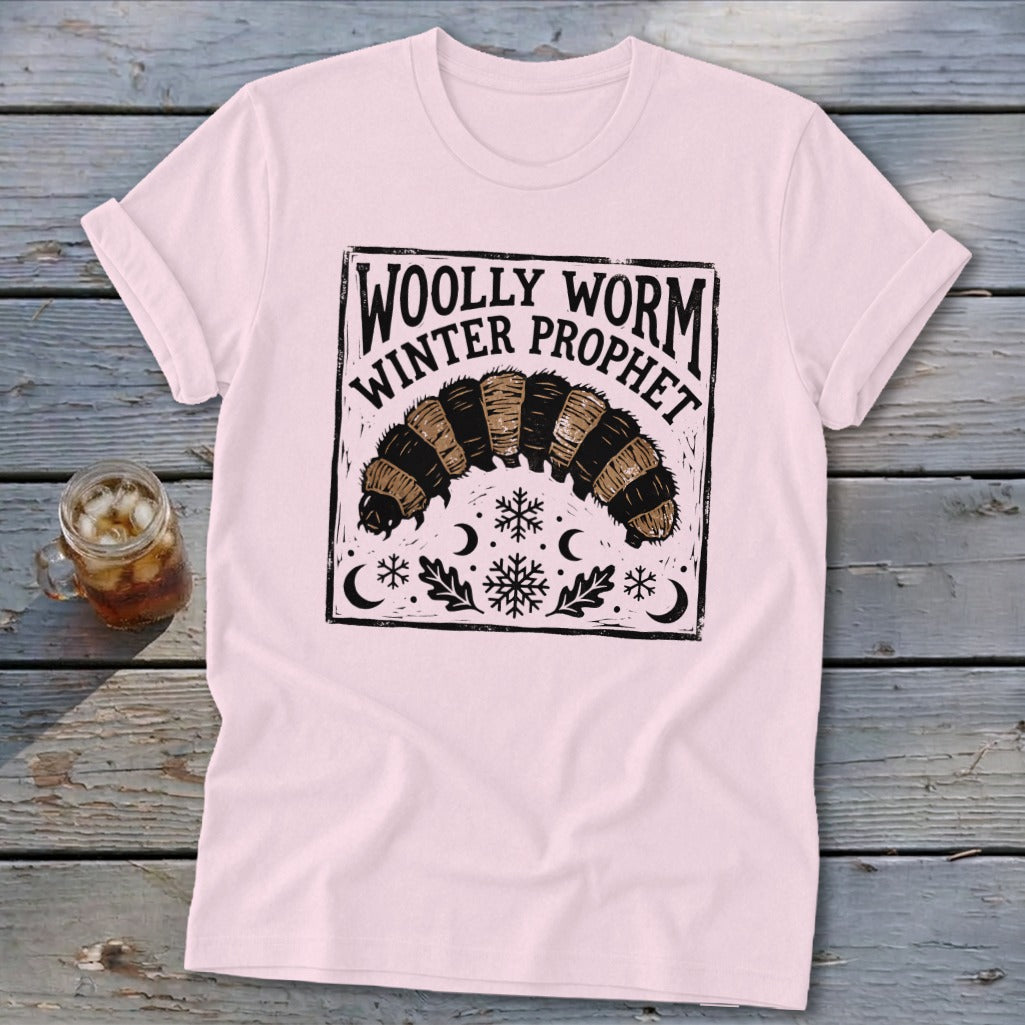 Light pink crewneck t-shirt featuring a black block-print graphic of a woolly worm and text reading Woolly Worm Winter Prophet.