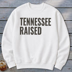 White crewneck sweatshirt with "TENNESSEE RAISED" printed in dark gray text.