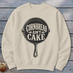 Cream sweatshirt with black graphic of a cast iron skillet and text: Cornbread Ain't Cake.