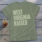 Olive green t-shirt with "WEST VIRGINIA RAISED" text in pale yellow.