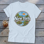 White t-shirt with circular New York landscape graphic featuring mountains, river, trees, deer, and sun.