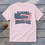 Light pink t-shirt with American flag graphic and text "Alabama Raised American Made".
